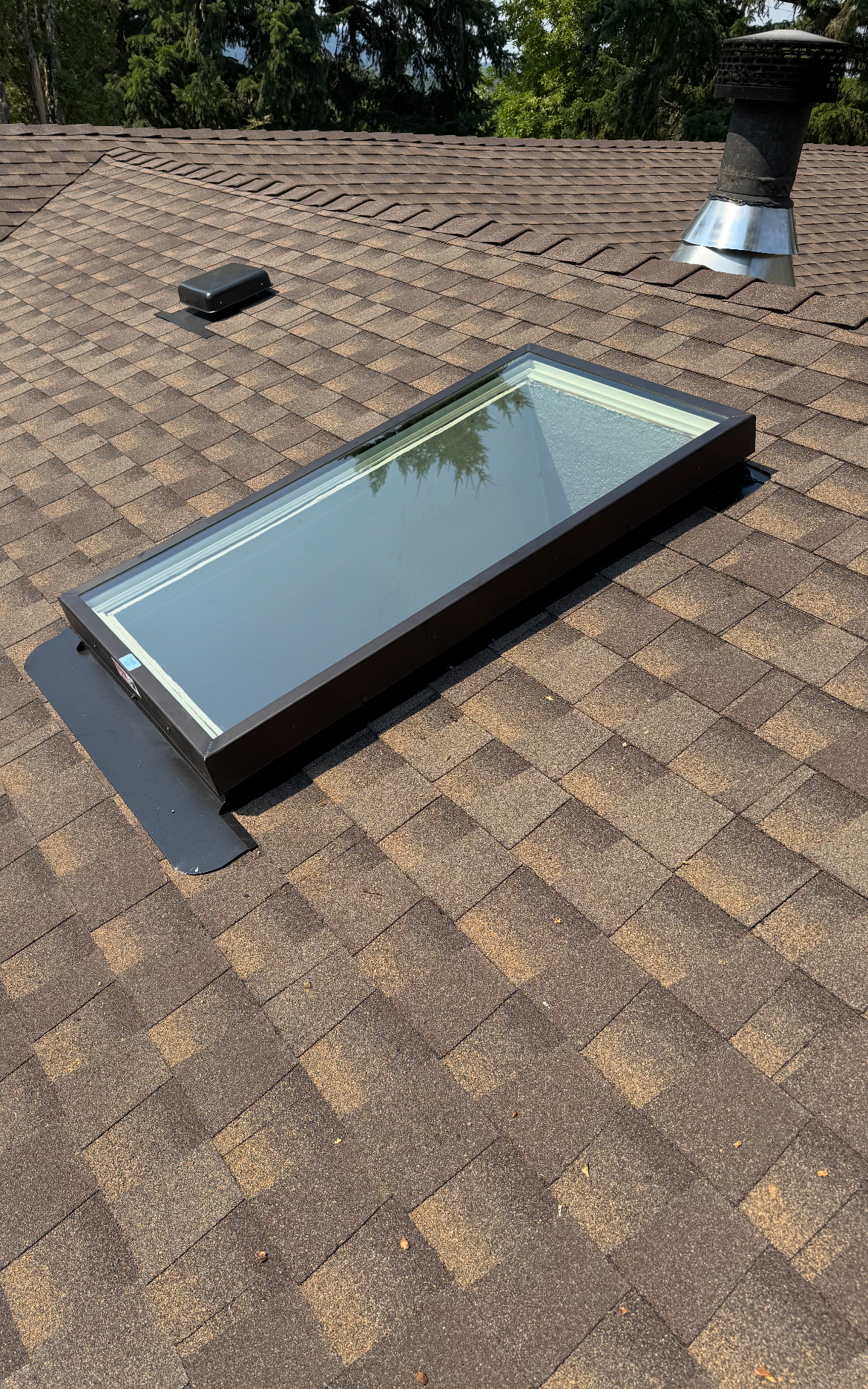 Close-up of a skylight flashing installed cleanly into a finished shingle roof