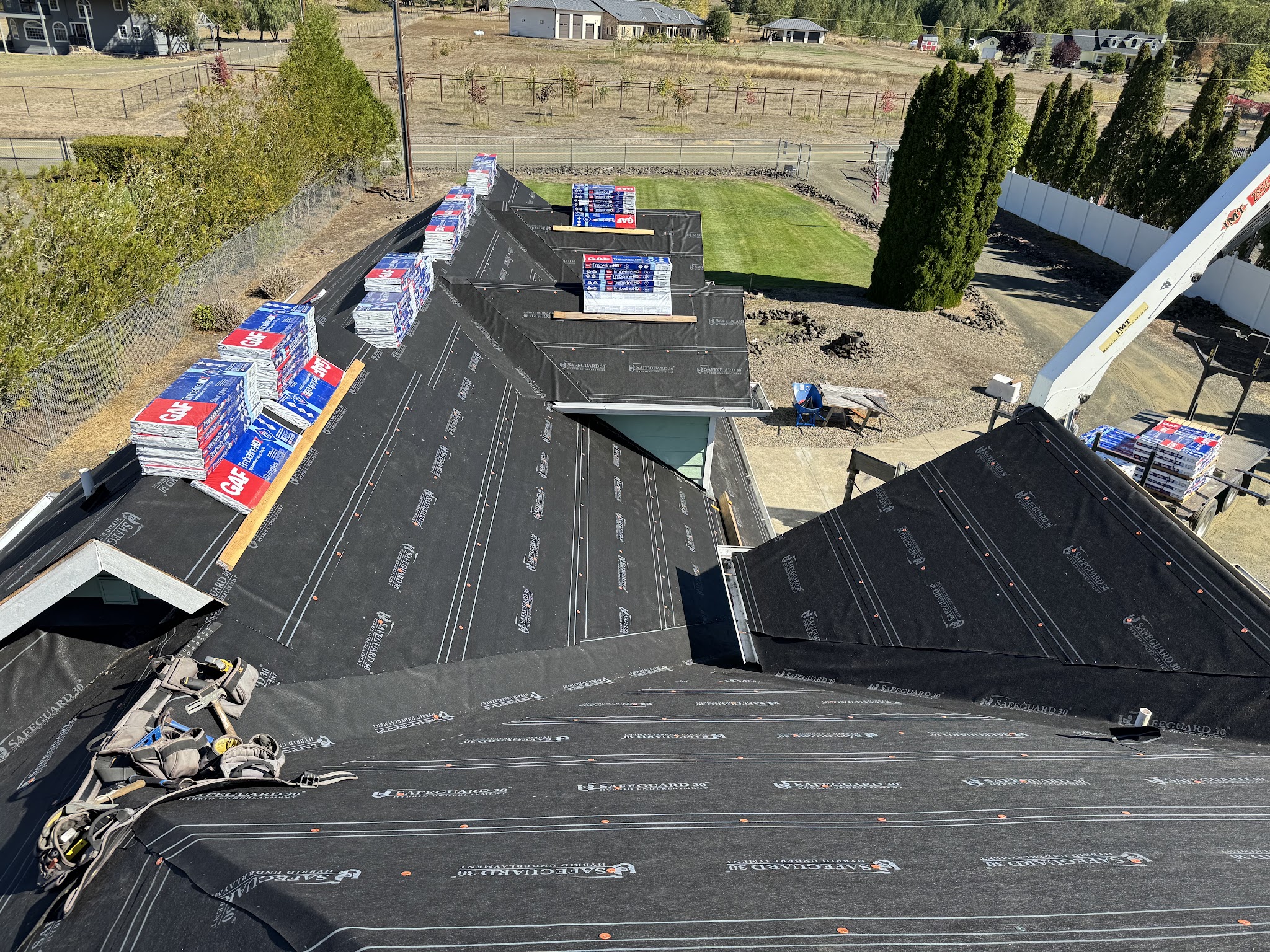 Roof deck with underlayment installed and stacked GAF shingle bundles staged for the next phase